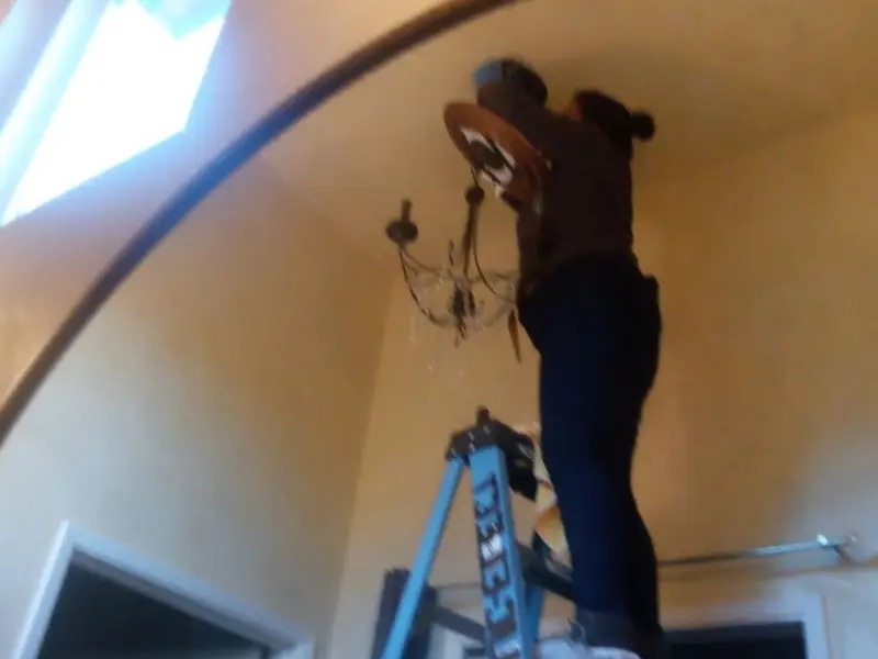 Electrician installing a chandelier in a Clayton residence